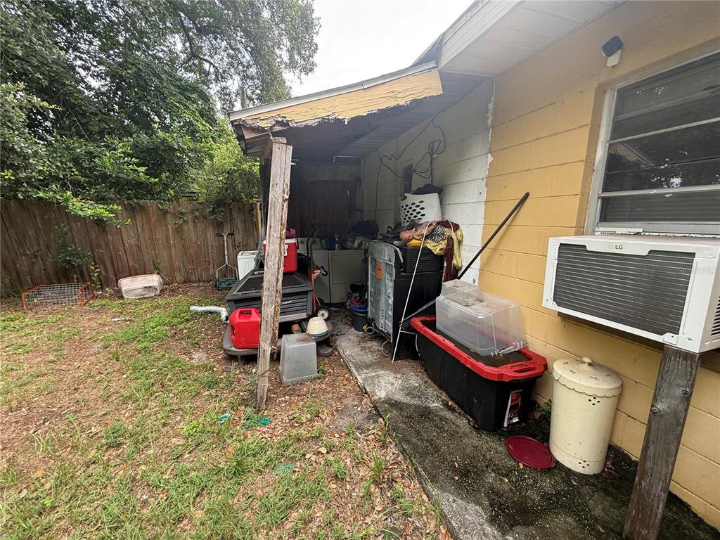 An outdoor storage area with a damaged roof overhang, cluttered with appliances and plastic bins — 4108 DELRAY AVENUE, ORLANDO, FL