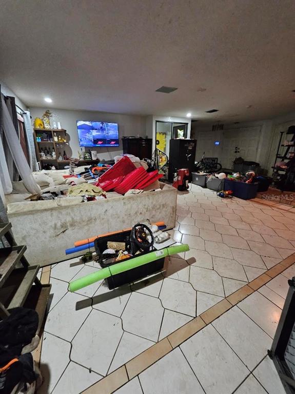 A living room features a large sectional sofa, tiled floors, and various storage bins and items — 1826 NW COUNTY ROAD 661, ARCADIA, FL