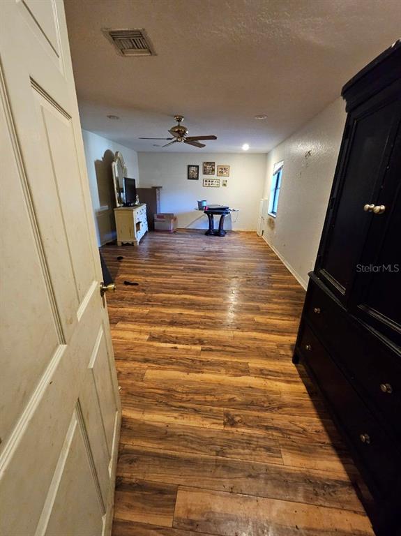 A room with wood-look flooring, a ceiling fan, and a large black armoire — 1826 NW COUNTY ROAD 661, ARCADIA, FL