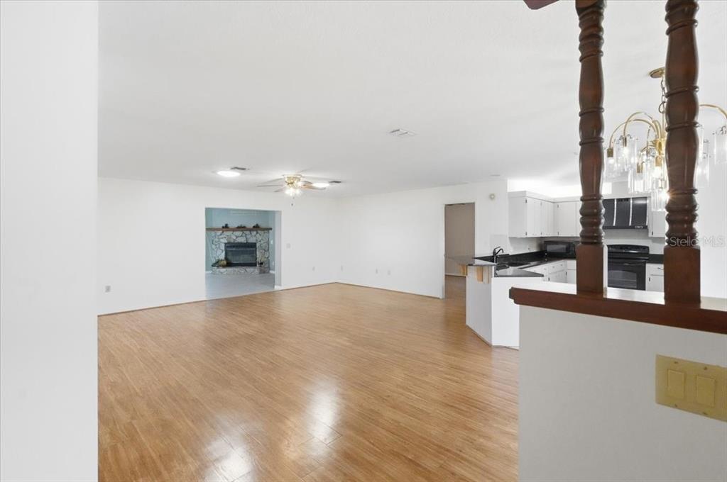 An open-concept living area with wood-look flooring, a kitchen, and a stone fireplace — 3002 S ROSE AVENUE, INVERNESS, FL