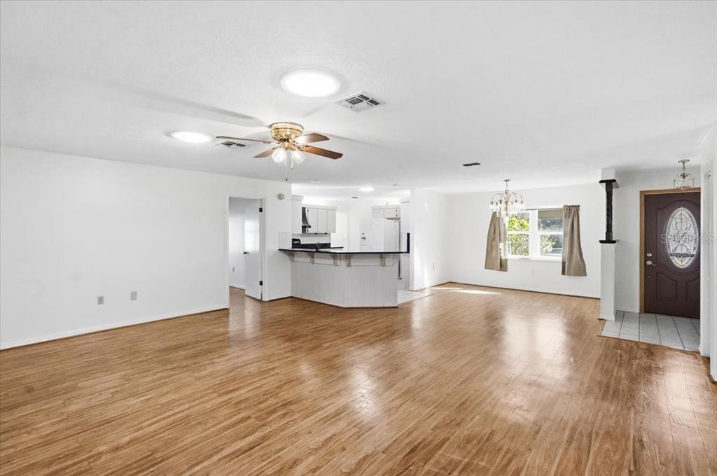 An open-concept living and dining area features wood-look flooring, a ceiling fan, and white walls — 3002 S ROSE AVENUE, INVERNESS, FL