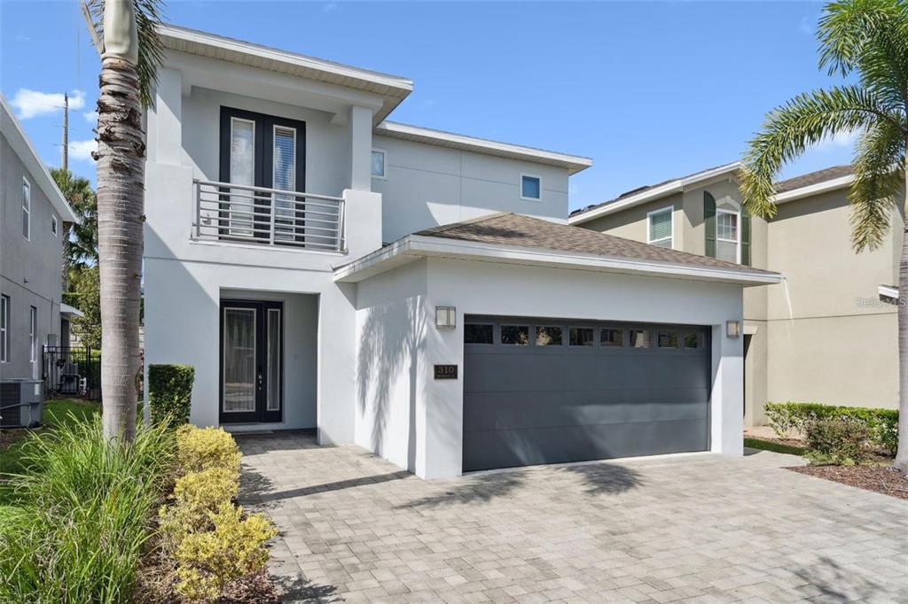 A two-story white house with a gray garage door and a second-floor balcony — 310 PENDANT COURT, KISSIMMEE, FL