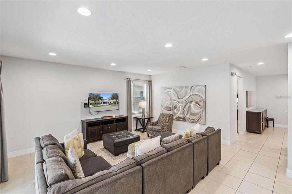 A living room features a large gray sectional sofa, a television, and tile flooring — 310 PENDANT COURT, KISSIMMEE, FL