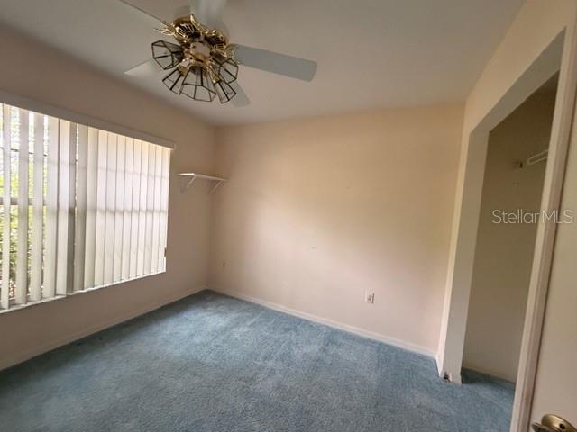 A bedroom with light-colored walls, blue carpeting, a ceiling fan, and vertical window blinds — 4268 N MAE WEST WAY, BEVERLY HILLS, FL
