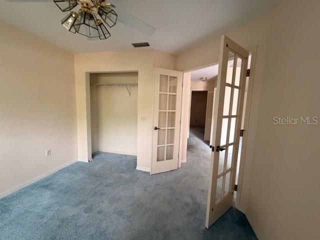 A bedroom with blue carpet, a ceiling fan, a closet, and French doors — 4268 N MAE WEST WAY, BEVERLY HILLS, FL