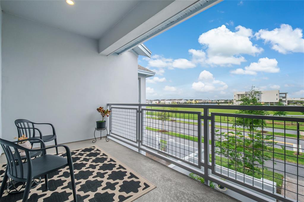 A covered balcony features a metal railing, two chairs, a patterned rug, and outdoor views — 10009 PEARSON AVENUE, ORLANDO, FL