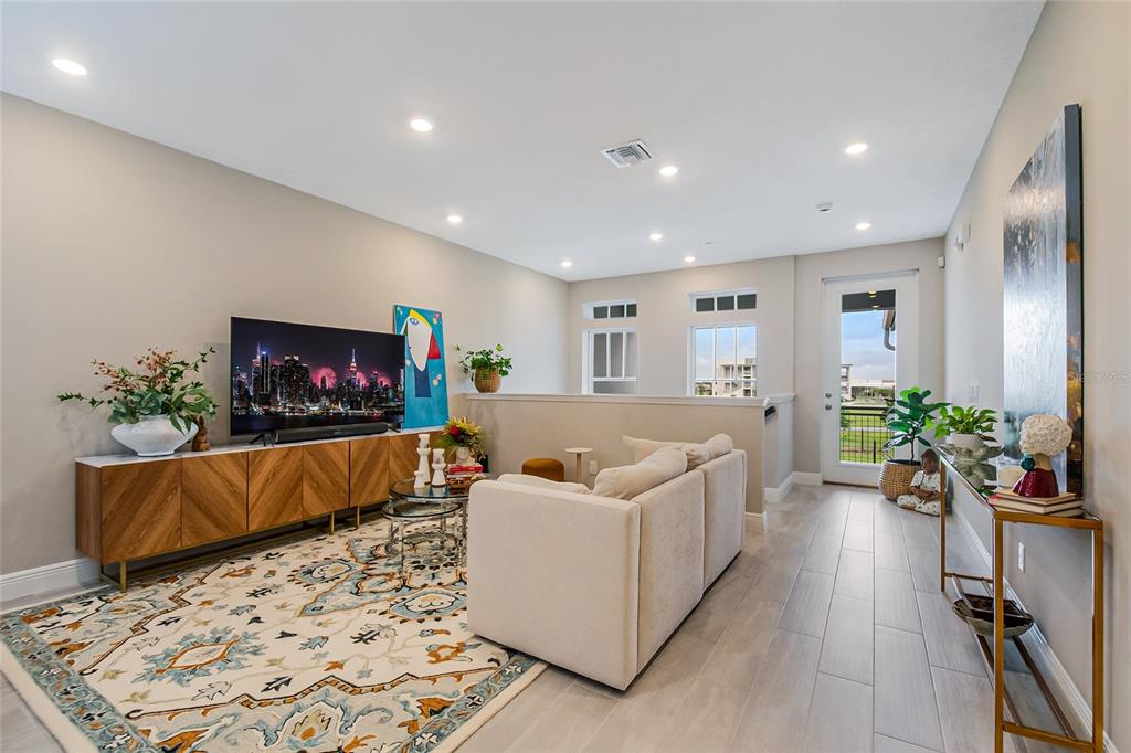 A modern living room features a beige sofa, patterned area rug, and a wood media console — 10009 PEARSON AVENUE, ORLANDO, FL