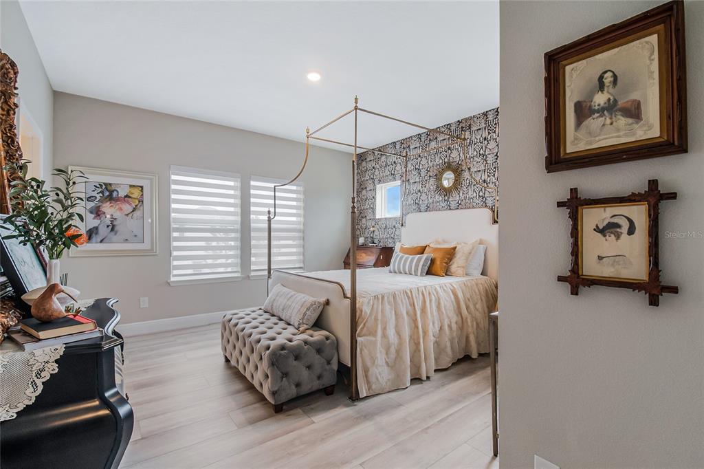 A bedroom features a canopy bed, patterned wallpaper, a tufted bench, and framed wall art — 10009 PEARSON AVENUE, ORLANDO, FL