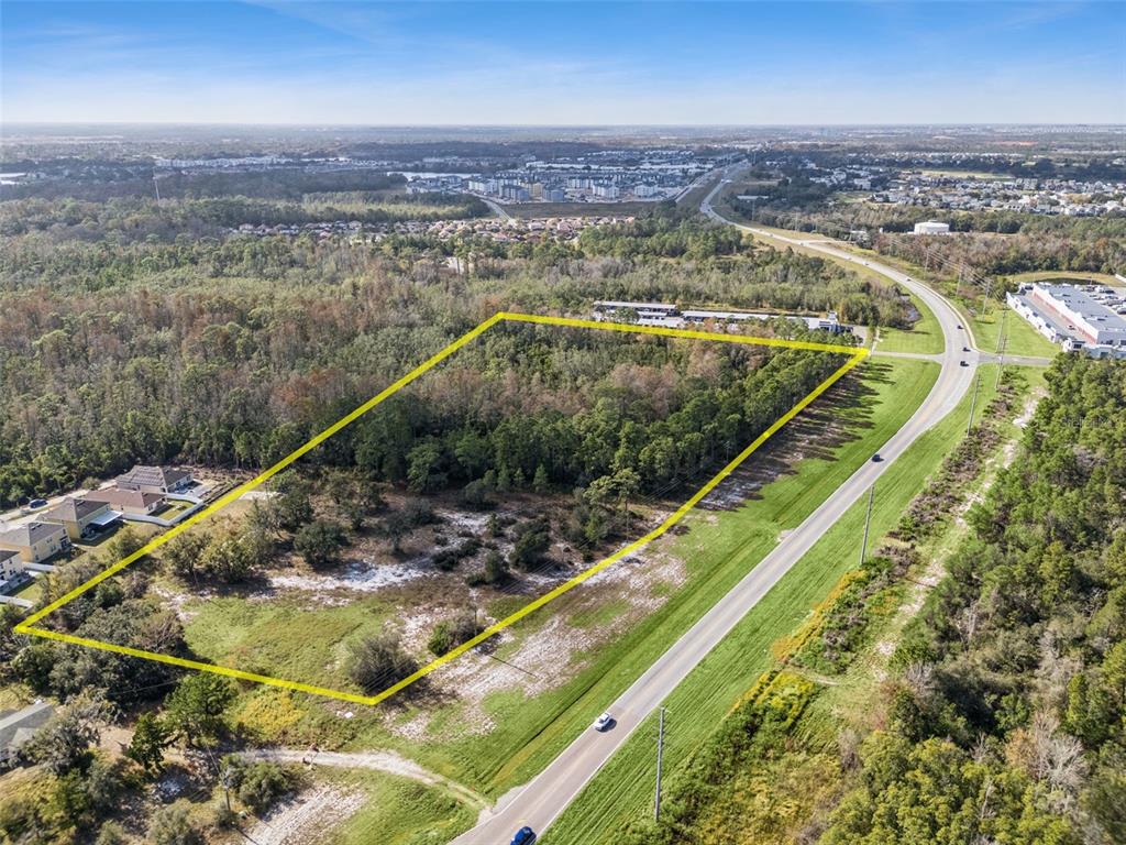 An aerial view shows a rectangular plot of undeveloped land outlined in yellow near a road — OSCEOLA POLK LINE ROAD, DAVENPORT, FL