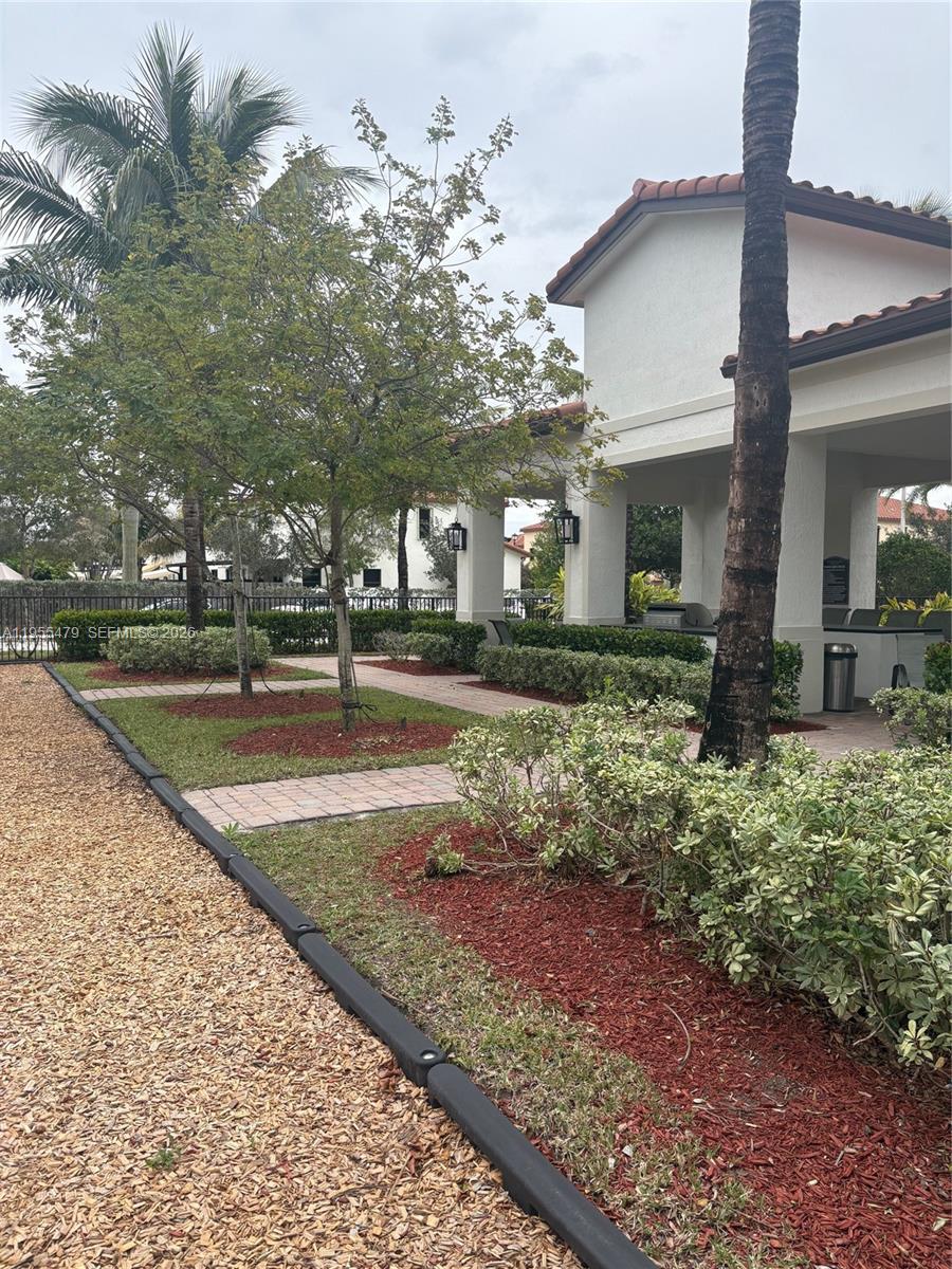 A paved walkway leads to a covered outdoor patio area with landscaping and trees — 15062 SW 177th Ter, Miami FL 33187, MIAMI, FL