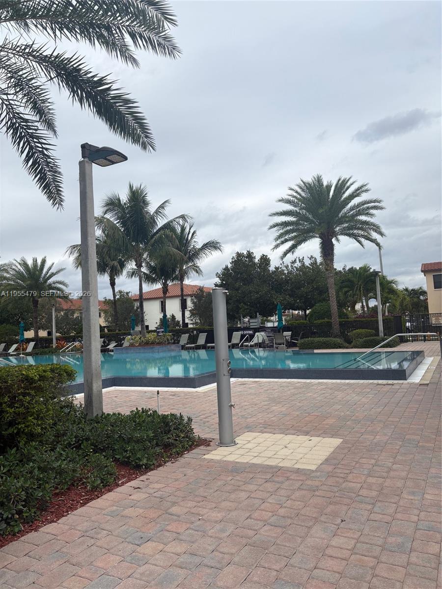 A swimming pool area features a paved deck, palm trees, and an outdoor shower — 15062 SW 177th Ter, Miami FL 33187, MIAMI, FL