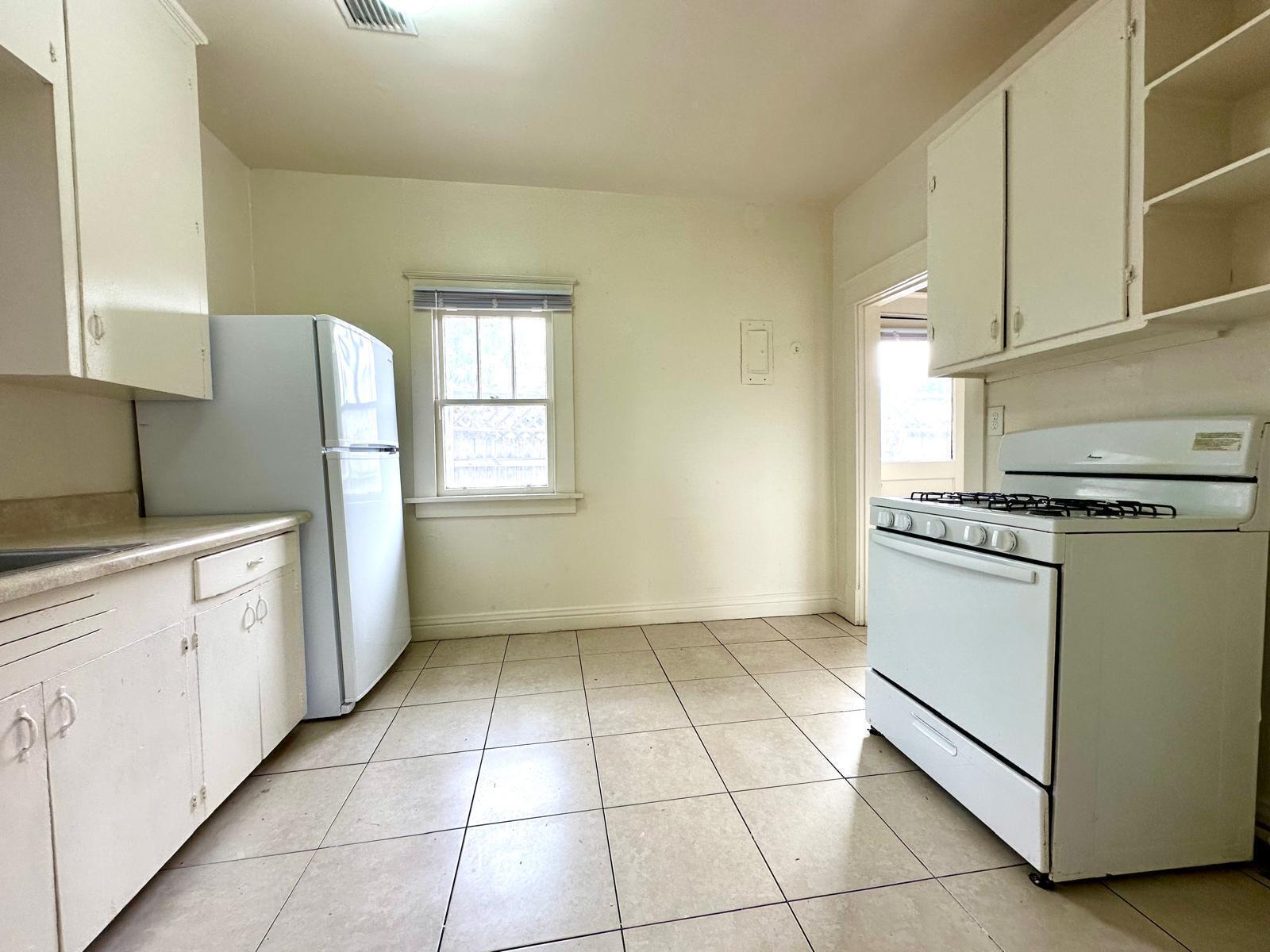 A kitchen with white cabinets, a refrigerator, a gas stove, and light-colored tile flooring — 523 Valley Forge Road, West Palm Beach FL 33405, WEST PALM BEACH, FL
