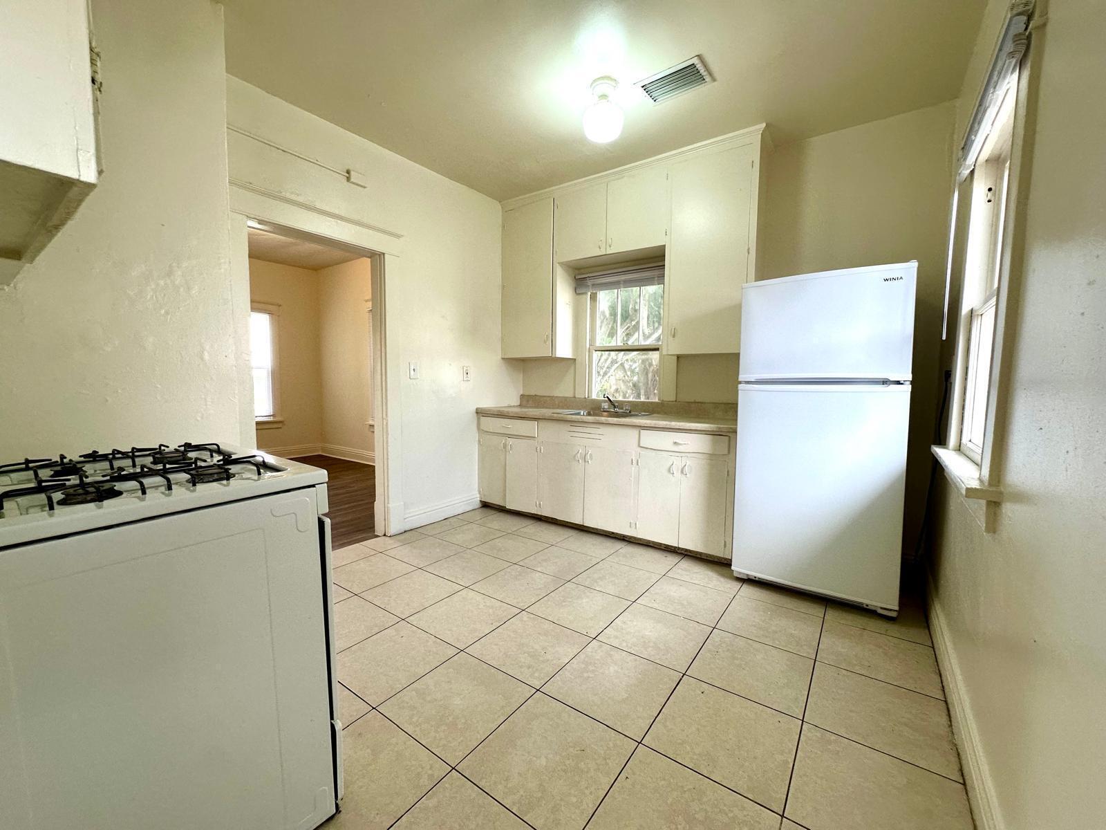A kitchen features white cabinets, a gas stove, a refrigerator, and light-colored tile flooring — 523 Valley Forge Road, West Palm Beach FL 33405, WEST PALM BEACH, FL