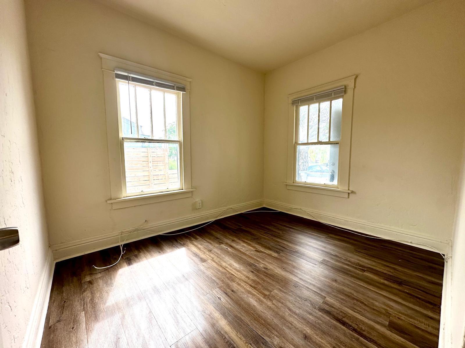 An empty room with light-colored walls, two windows, and dark wood-look flooring — 523 Valley Forge Road, West Palm Beach FL 33405, WEST PALM BEACH, FL