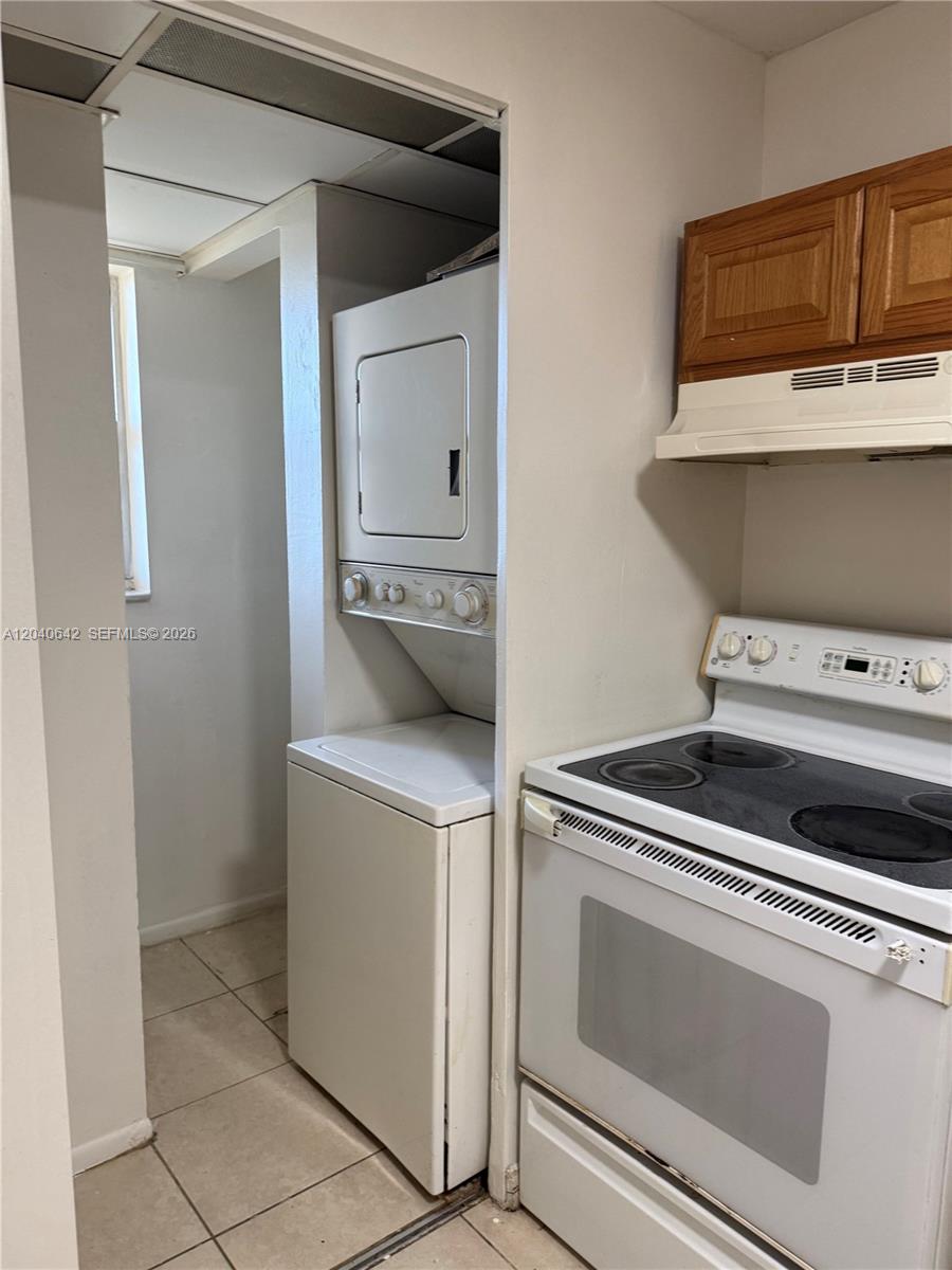 A kitchen features a white electric stove and a stacked washer and dryer unit — TAMARAC, FL
