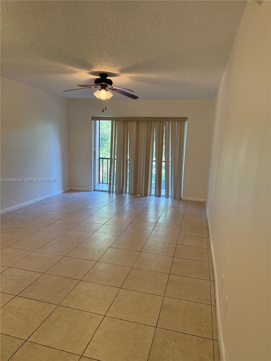 A living room features beige tile flooring, a ceiling fan, and sliding glass balcony doors — TAMARAC, FL