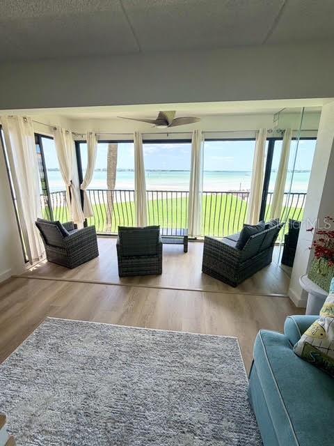 A sunroom with wicker furniture and light wood flooring overlooks a beach and ocean — 865 S GULFVIEW BOULEVARD UNIT 202, CLEARWATER BEACH, FL