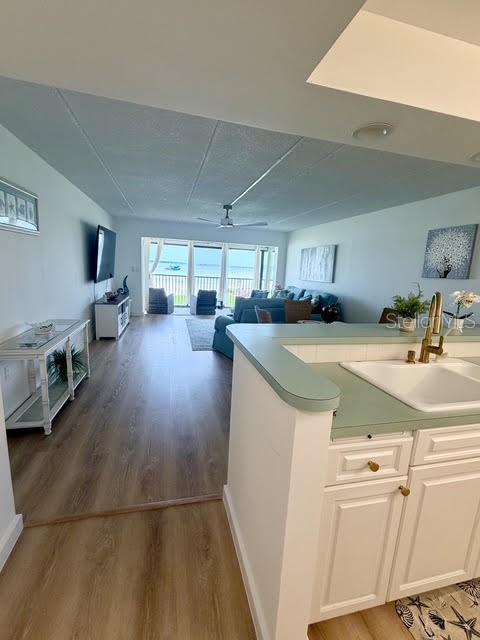 A kitchen counter overlooks a living room with wood-look flooring and a view of the ocean — 865 S GULFVIEW BOULEVARD UNIT 202, CLEARWATER BEACH, FL