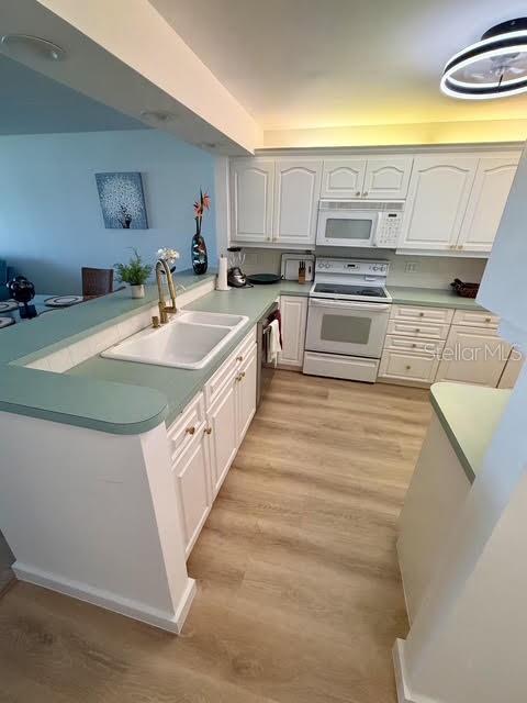 A kitchen with white cabinets, light green countertops, and light wood-look flooring — 865 S GULFVIEW BOULEVARD UNIT 202, CLEARWATER BEACH, FL