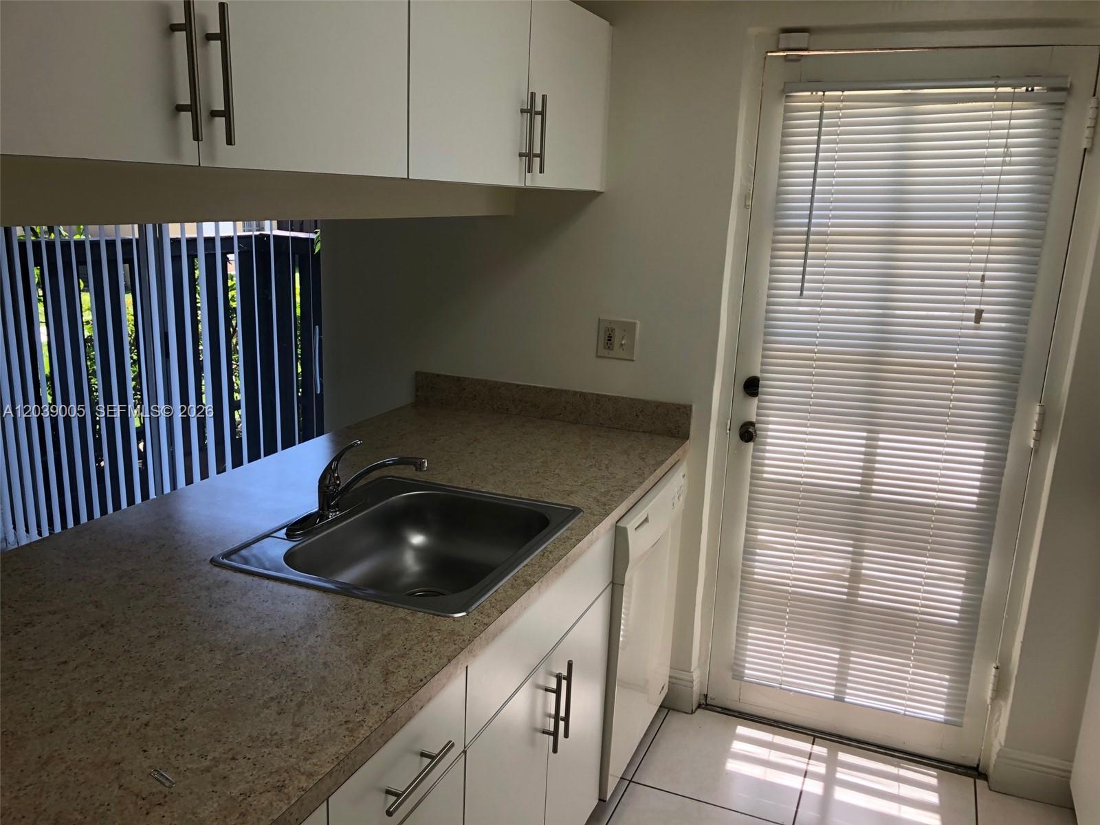 A kitchen features white cabinets, a stainless steel sink, tan countertops, and a glass door — 10808 N Kendall Dr # 4, Miami FL 33176, MIAMI, FL