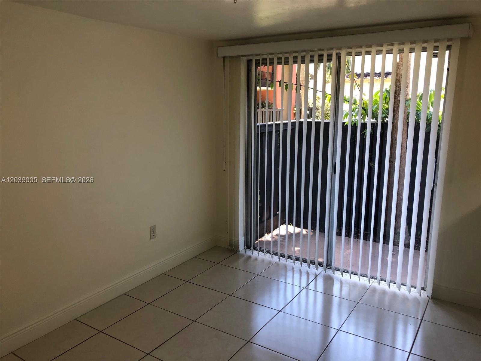 A room with light-colored tile flooring and vertical blinds covering a sliding glass door — 10808 N Kendall Dr # 4, Miami FL 33176, MIAMI, FL