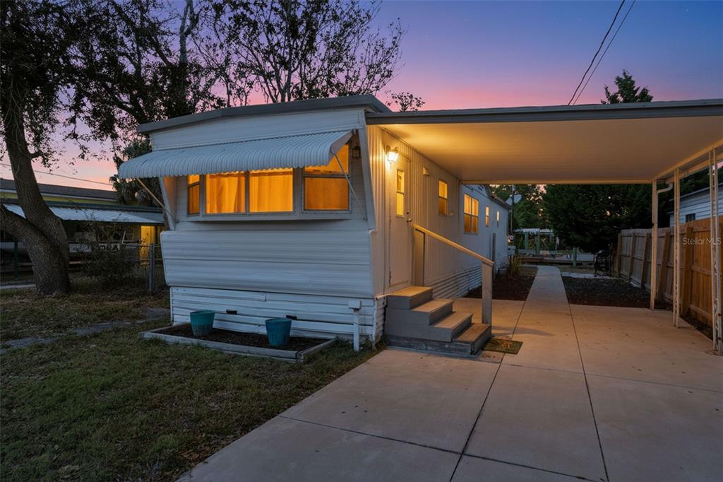 A white mobile home with a carport and concrete driveway at sunset — 6727 ALBATROSS LANE, HUDSON, FL