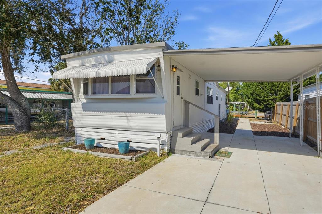 A white mobile home with a metal awning and a concrete carport — 6727 ALBATROSS LANE, HUDSON, FL
