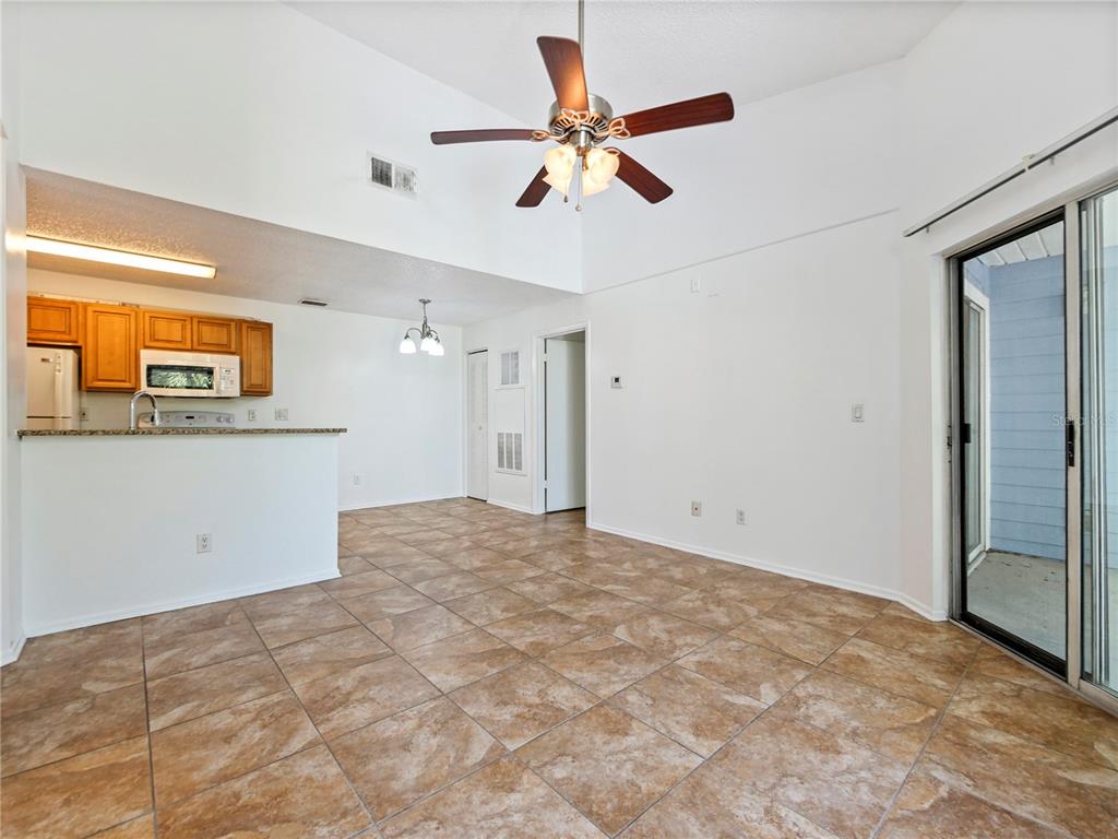 An open-concept living and dining area features vaulted ceilings, tile flooring, and a kitchen pass-through — 2569 GRASSY POINT DRIVE UNIT 309, LAKE MARY, FL