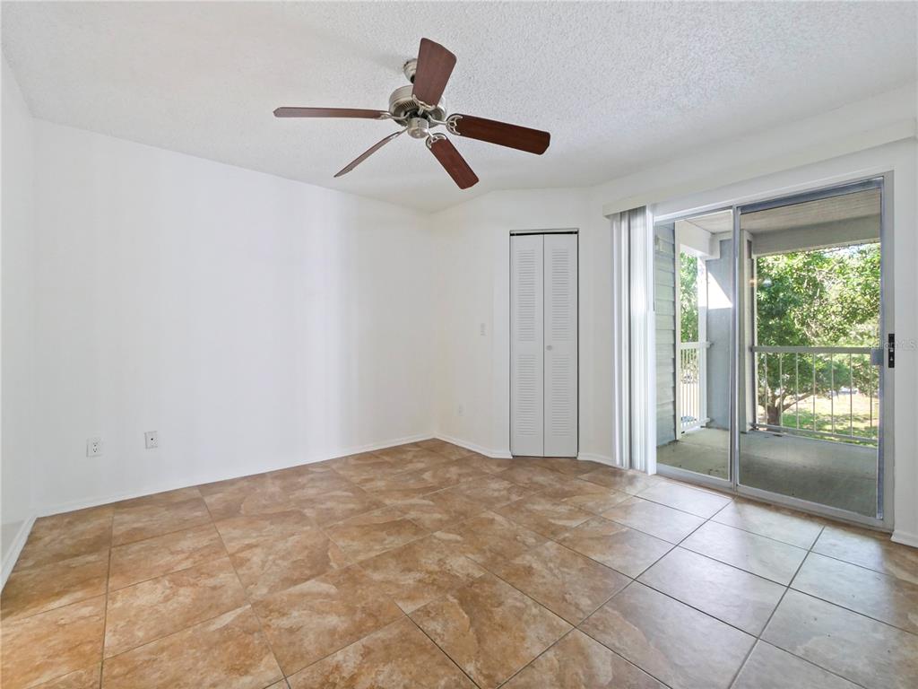 An empty room features tan tile flooring, a ceiling fan, a closet, and sliding glass doors — 2569 GRASSY POINT DRIVE UNIT 309, LAKE MARY, FL