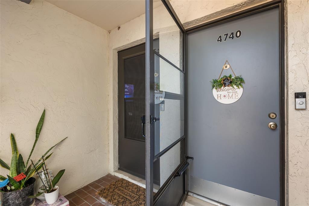 An exterior view shows a gray front door with a welcome sign and screen door — 4740 AVON COURT UNIT 4740, ST CLOUD, FL