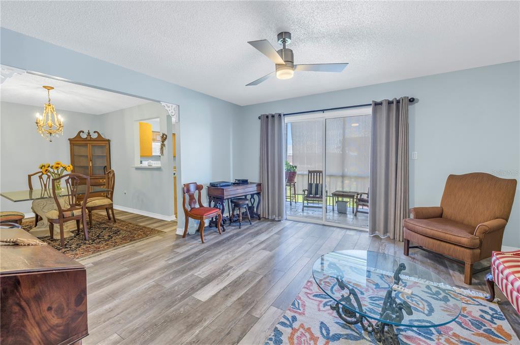 A living room with light blue walls, wood-look flooring, a ceiling fan, and sliding glass doors — 4115 34TH WAY S UNIT 195, ST PETERSBURG, FL