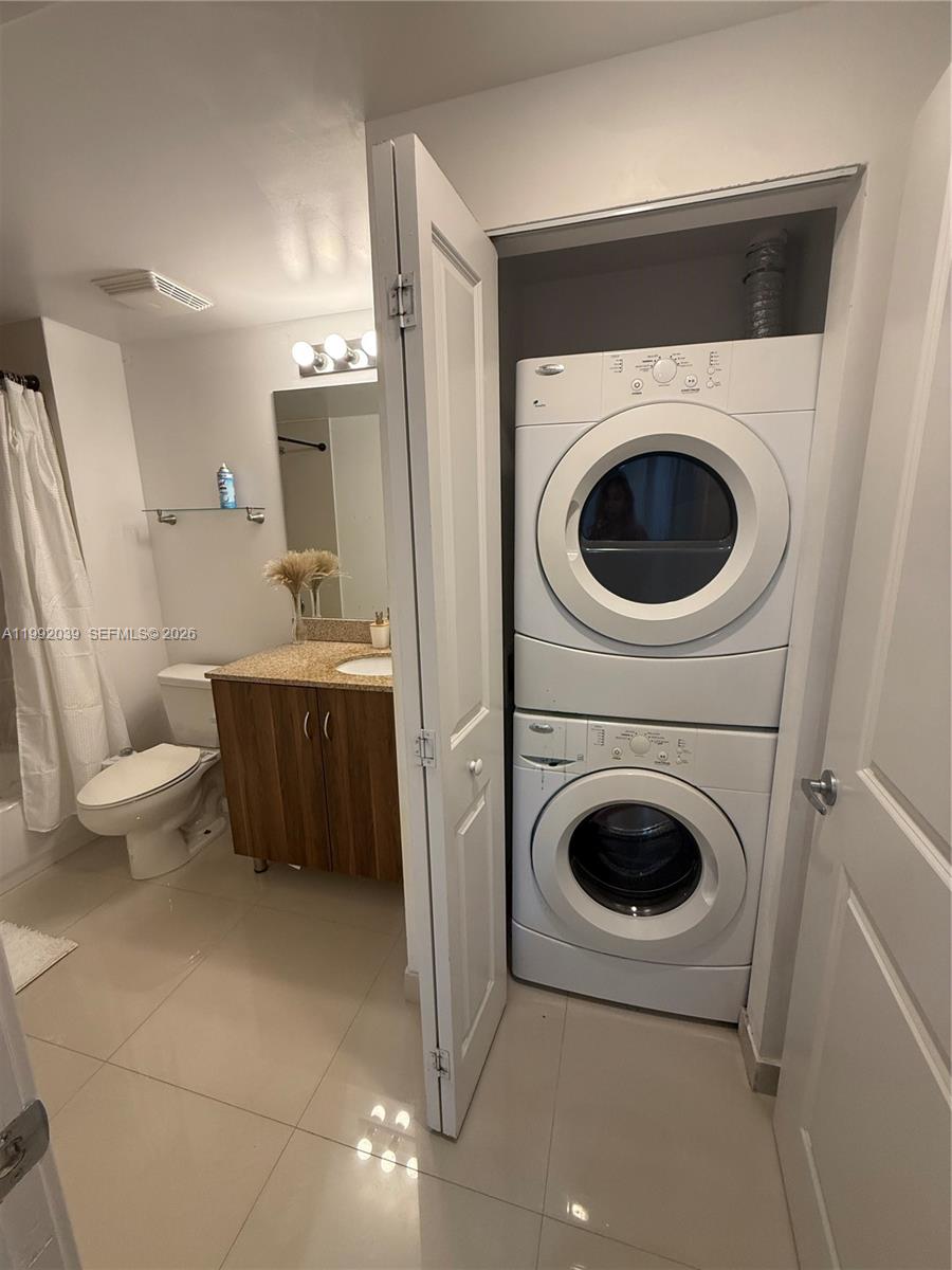 A bathroom features a vanity, toilet, shower, and a stacked washer and dryer unit — 601 NE 23rd St # 901, Miami FL 33137, MIAMI, FL