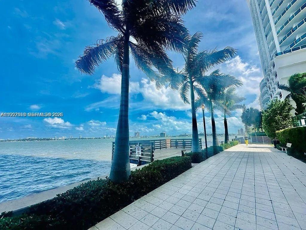 A paved walkway runs alongside a waterfront area with palm trees and a tall building — 601 NE 23rd St # 901, Miami FL 33137, MIAMI, FL