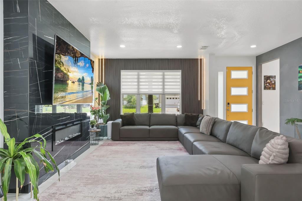 A living room features a black marble fireplace, a large gray sectional, and a yellow door — 2518 EMPRESS DRIVE, KISSIMMEE, FL