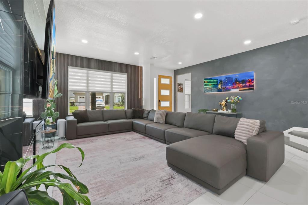 A modern living room features a large gray sectional sofa, dark accent walls, and tile flooring — 2518 EMPRESS DRIVE, KISSIMMEE, FL