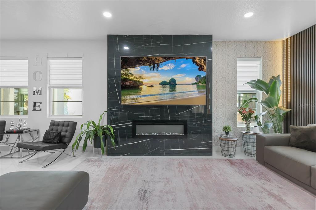 A modern living room features a black marble fireplace wall with a mounted television — 2518 EMPRESS DRIVE, KISSIMMEE, FL
