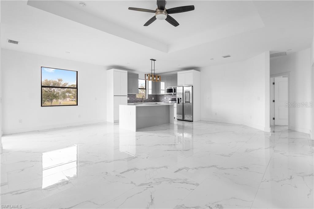 A modern open-concept kitchen and living area features white cabinetry, a center island, and flooring — 1806 NE 21ST PLACE, CAPE CORAL, FL