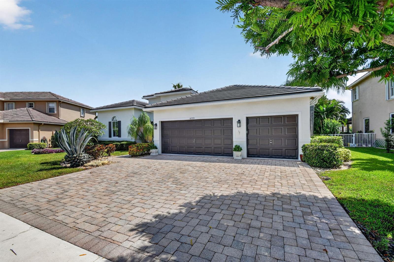 A single-story house with a paved driveway, a three-car garage, and a landscaped front yard — 6733 Finamore Circle, Lake Worth FL 33467, LAKE WORTH, FL