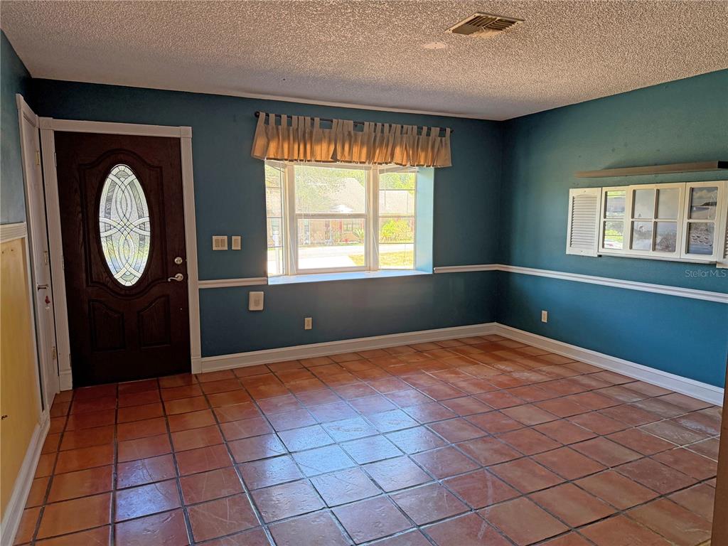 An empty room with blue walls, a bay window, and terracotta tile flooring — 17 JUNIPER TRACK DRIVE, OCALA, FL