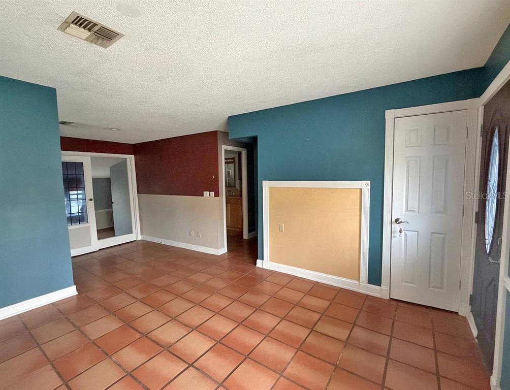 A room with terracotta tile flooring, teal and maroon walls, and a white door — 17 JUNIPER TRACK DRIVE, OCALA, FL