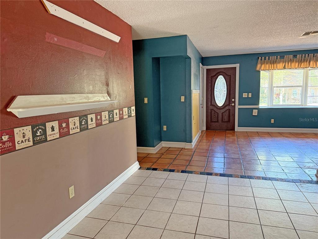 A room with a coffee-themed wallpaper border, brown walls, and a tiled entryway — 17 JUNIPER TRACK DRIVE, OCALA, FL