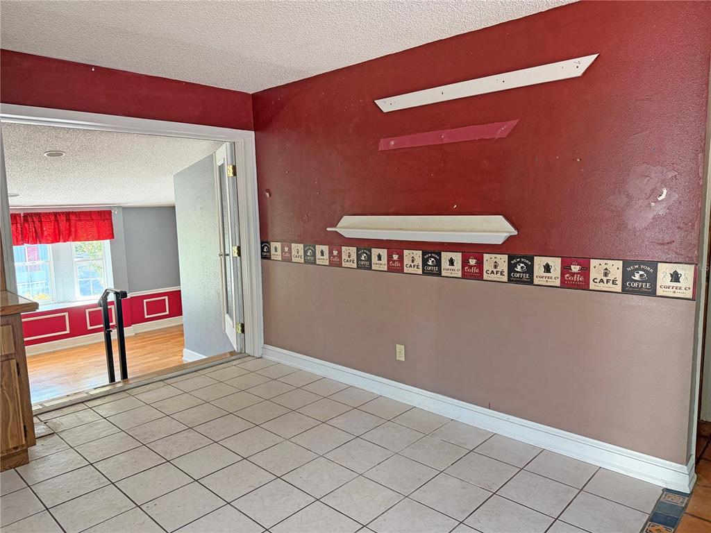 A tiled kitchen area features a red wall with a coffee-themed border and shelving — 17 JUNIPER TRACK DRIVE, OCALA, FL