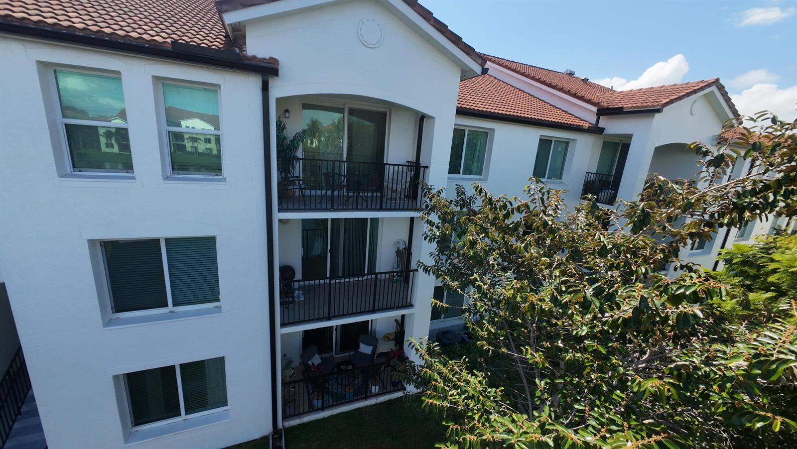Exterior view of a three-story white apartment building with balconies and a tiled roof — 822 Villa Circle, Boynton Beach FL 33435, BOYNTON BEACH, FL