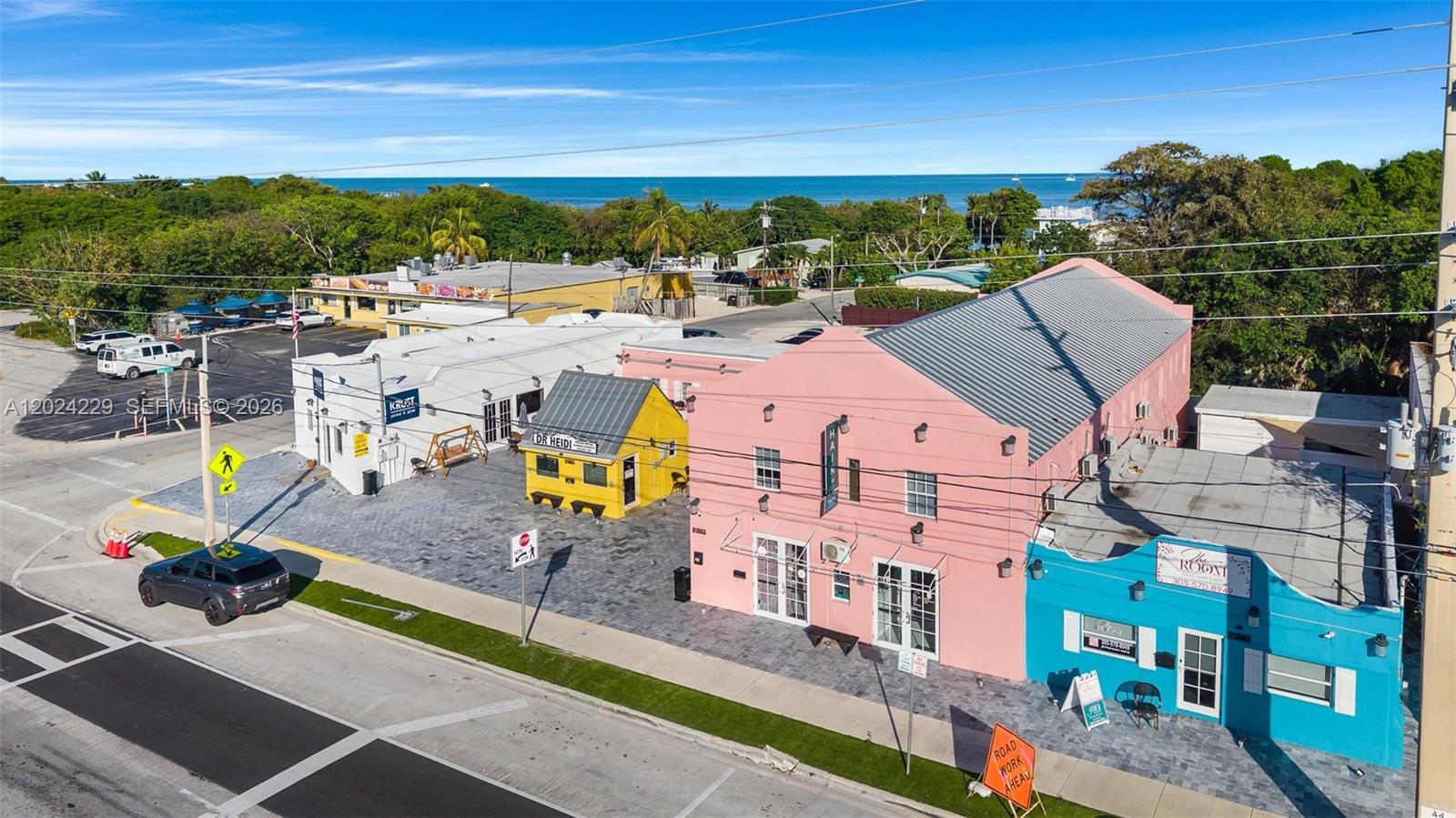 An aerial view shows a pink building, a yellow structure, and a blue storefront near water — 91865 Overseas Hwy, FL 33070, FL