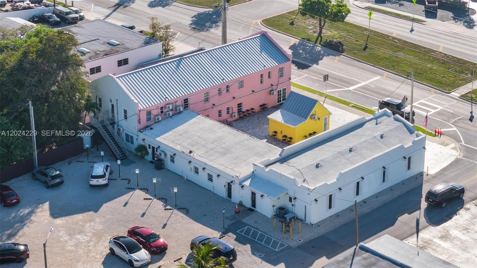 An aerial view shows a pink building, a yellow structure, and a white building with parking — 91865 Overseas Hwy, FL 33070, FL