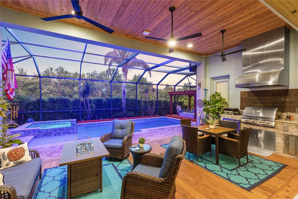 A covered outdoor patio features a swimming pool, dining area, and built-in stainless steel grill — 13391 ALDERLEY DRIVE, ORLANDO, FL