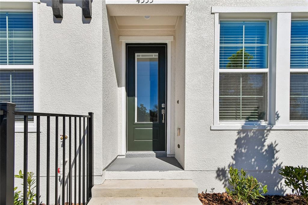 A white stucco exterior features a dark green front door with a glass panel — 4333 ROUSH AVENUE, ORLANDO, FL