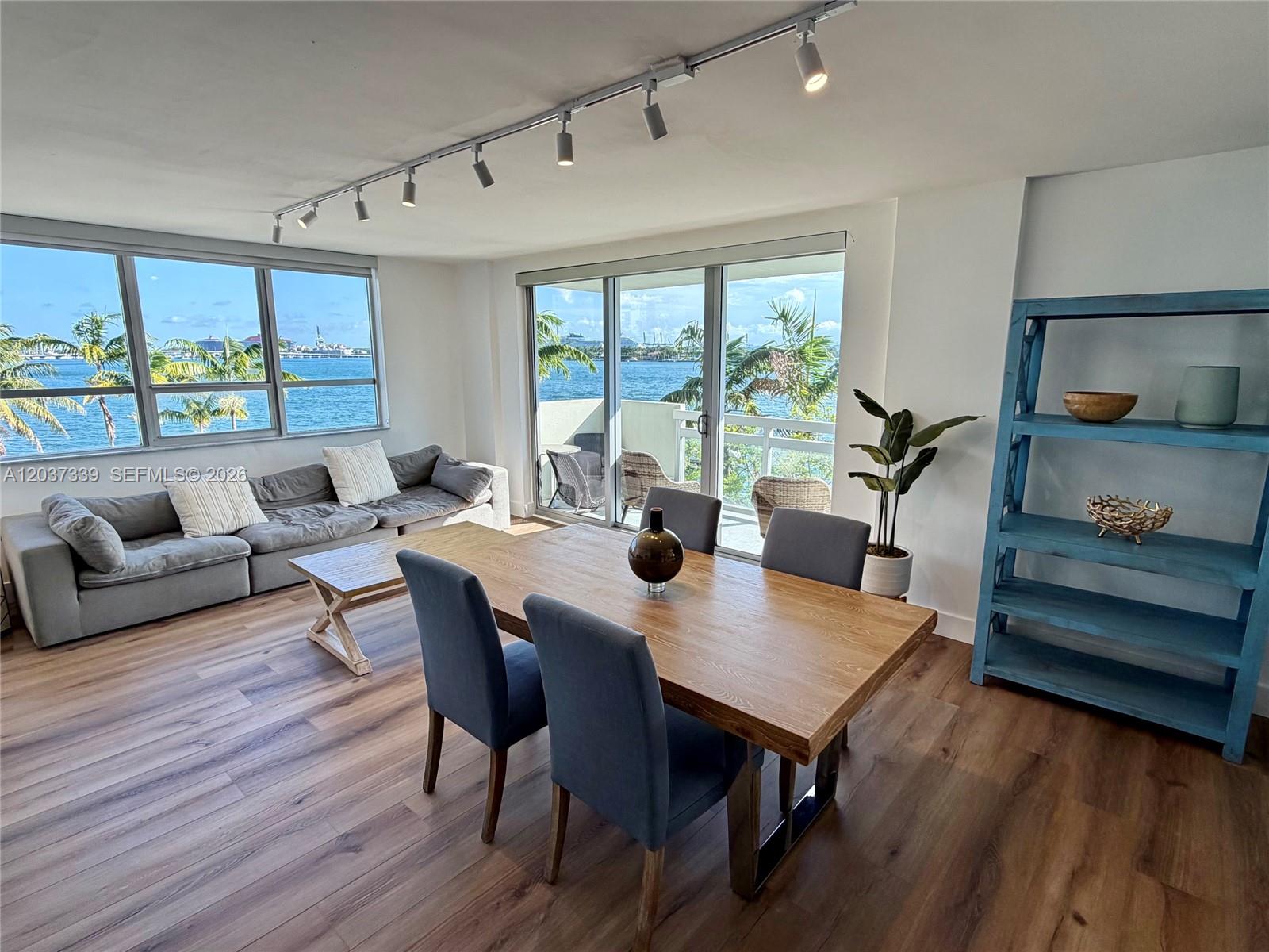 A dining and living area features wood floors, a waterfront view, and modern track lighting — 1500 Bay Rd # 338S, Miami Beach FL 33139, MIAMI BEACH, FL