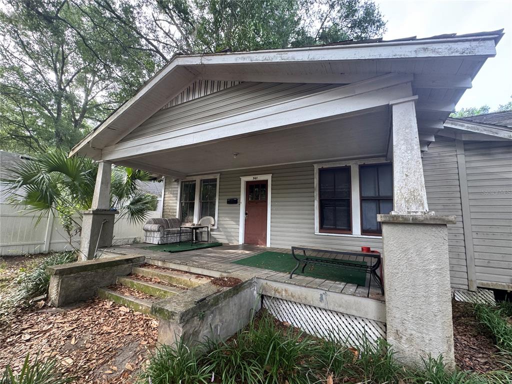 A single-story house with a covered front porch, wooden siding, and concrete steps — 907 NW 11TH AVENUE, GAINESVILLE, FL