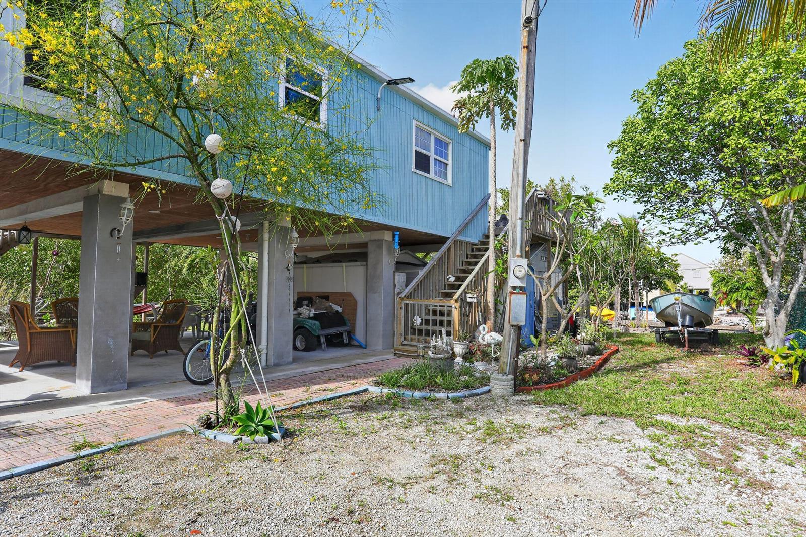 A light blue stilt house with an outdoor staircase, patio area, and a boat trailer — 27910 Porgie Path, FL 33042, FL